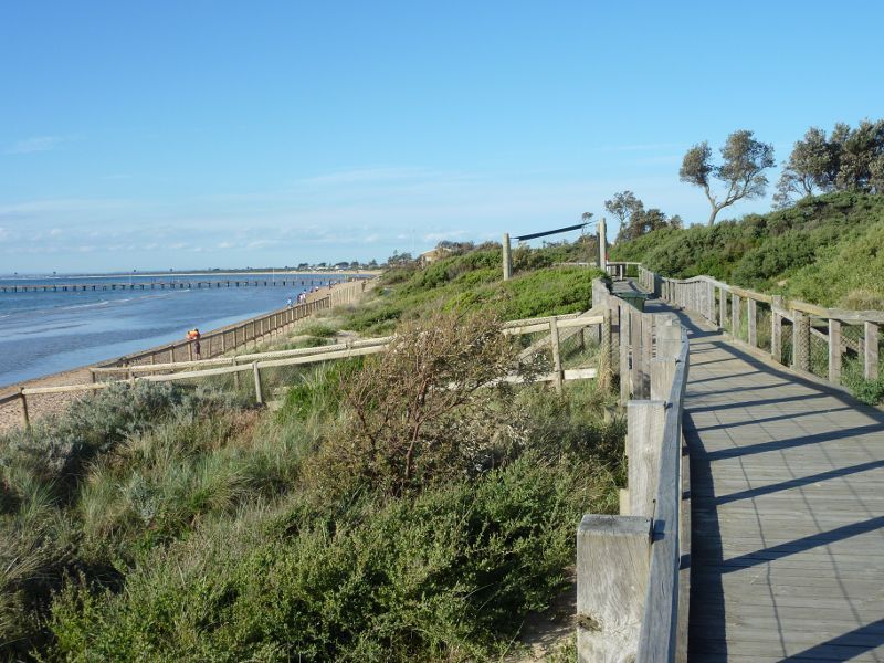 Frankston - Foreshore boardwalk and beach south of Frankston Pier: View north along boardwalk towards pier