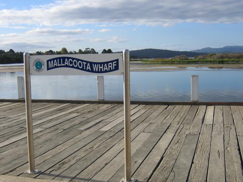 Mallacoota - Mallacoota Wharf, northern end of Buckland Drive: Sign at wharf, view north-east across Mallacoota Inlet