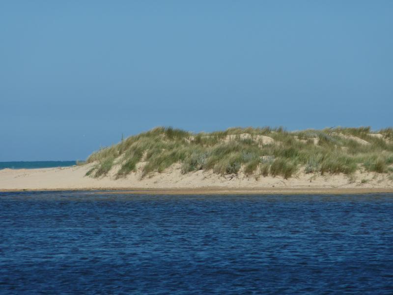Seaspray - Merriman Creek and fishing platform at the park at end of Foreshore Road: View across creek towards sand dunes from fishing platform